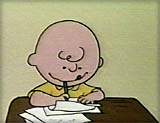 Charlie Brown writing with a pencil sticking his tongue out/biting it.