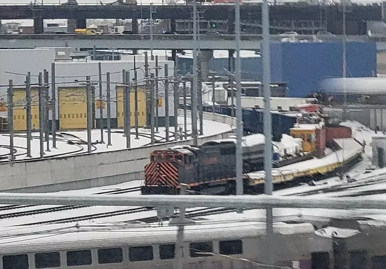 mystery black and yellow/orange frieght locomotive pulling caboose and some random other cars at somerville yard